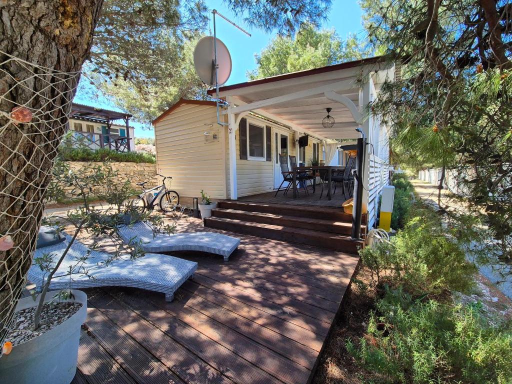 una piccola casa bianca con una terrazza in legno con tavolo di Mobile home BLUE CLASS B4 a Jezera