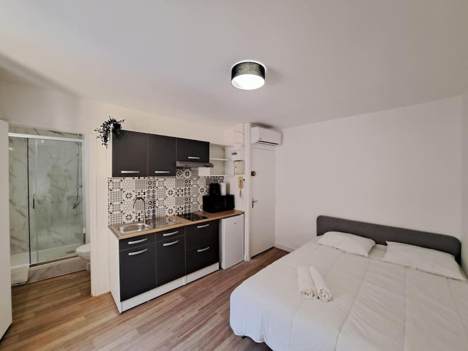 a bedroom with a white bed and a kitchen at Palerme - Appart'city in Reims