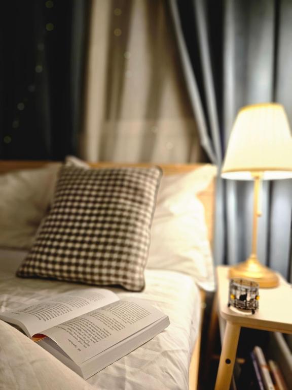 een boek op een bed met een kussen en een lamp bij Greta Hillside 