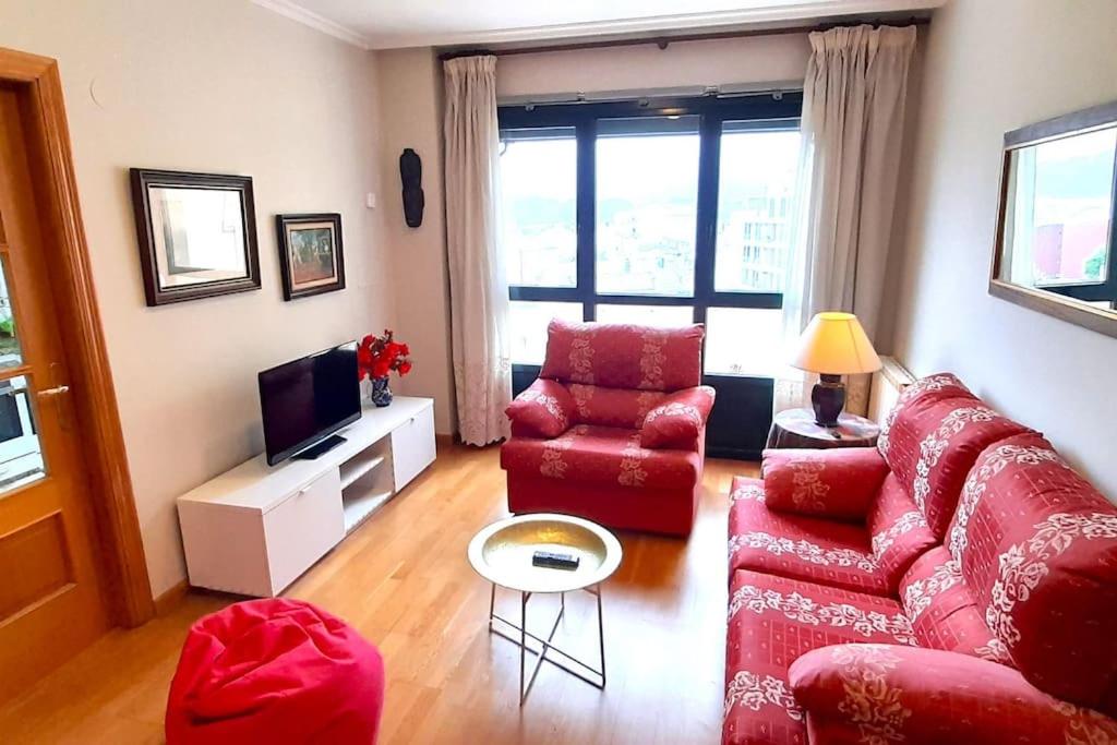 sala de estar con sofá rojo y silla en Apartamento 3 Dormitorios Playa Foz, en Foz