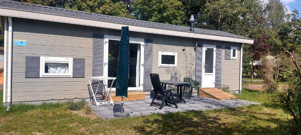 ein Haus mit einem Tisch und einem Stuhl auf einer Terrasse in der Unterkunft Chalet type F in Voorthuizen