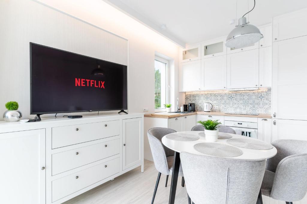 a kitchen with a tv and a table with chairs at Belle View - 3pok, nawet 5 łóżek, piękny widok na rzekę, TV55" z Netflix i Max, parking, winda in Iława
