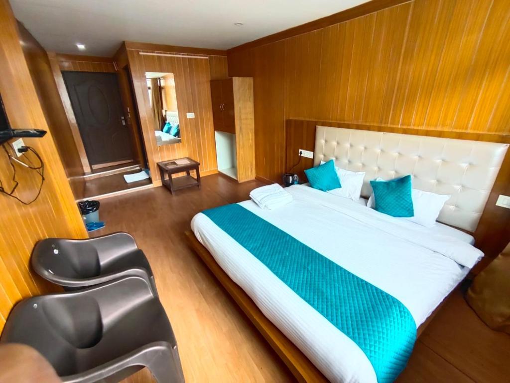 een slaapkamer met een groot wit bed met blauwe kussens bij Thesleepingbeautyhotel in Joshimath