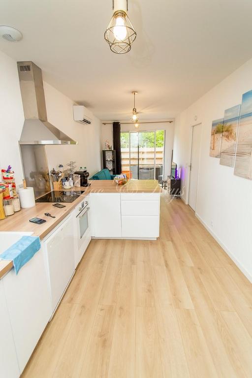 une cuisine avec des armoires blanches et un plancher en bois dans l'établissement Jolie Maison en pleine nature-proche du lac, à Parentis-en-Born