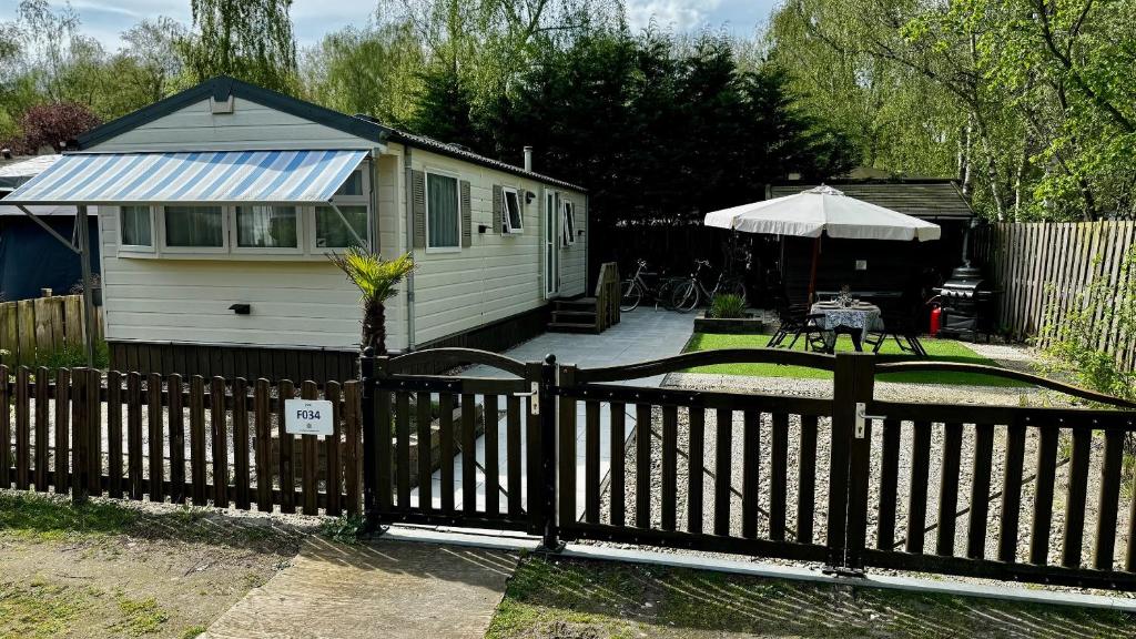 a fence in front of a house with an umbrella at PURE - Chalet Zeeland - Air conditioning and washing machine in Hoek