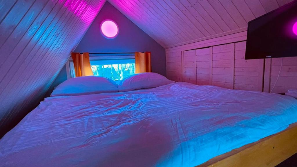 Cama en habitación con luces rosas y azules en Privátní wellness domek RockStar en Smržovka