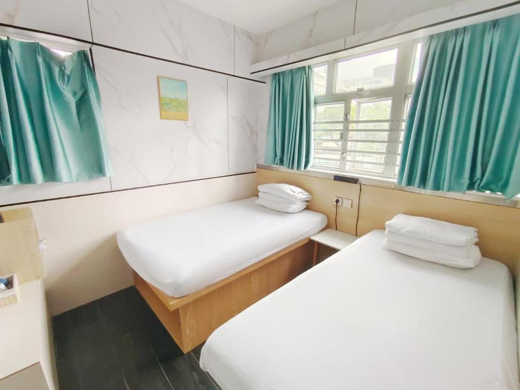 twee bedden in een kleine kamer met groene gordijnen bij i-Hostel (Cameron Road) in Hong Kong