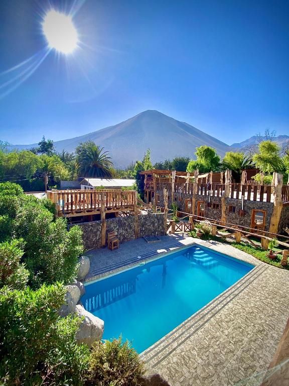 uma piscina com uma montanha ao fundo em Cabañas Rusticas Olimpus del Elqui em Vicuña