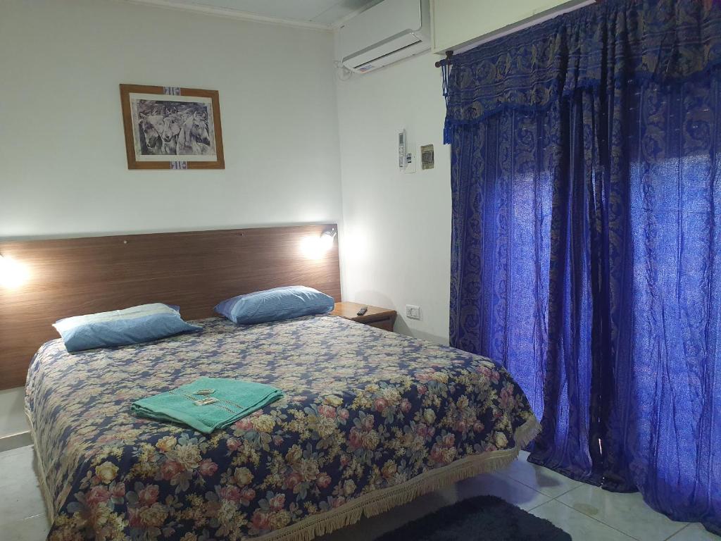 um quarto com uma cama com cortinas azuis em Monza alojamiento. em Chajarí