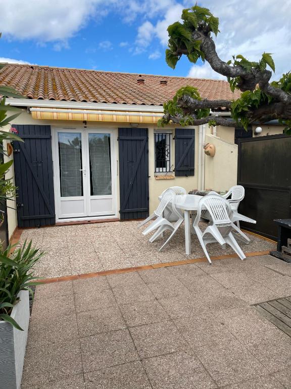a patio with a table and chairs in front of a house at résidence les amandines in Gruissan
