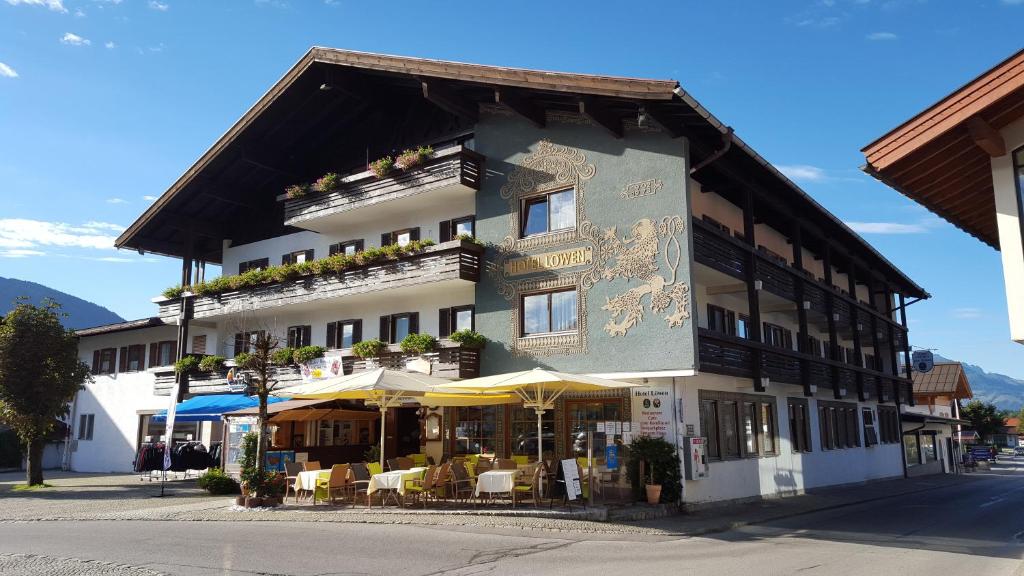 a building with tables and chairs in front of it at Hotel Löwen in Reit im Winkl