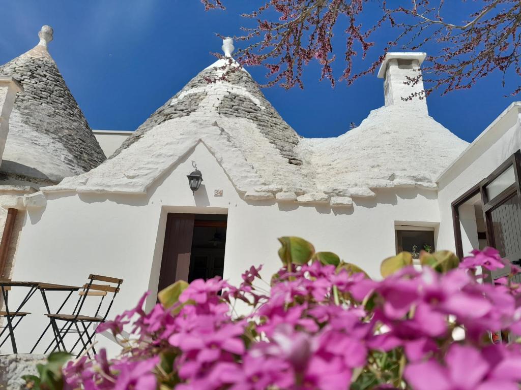 a white house with a roof with purple flowers at Trullo Il Giglio in Cisternino