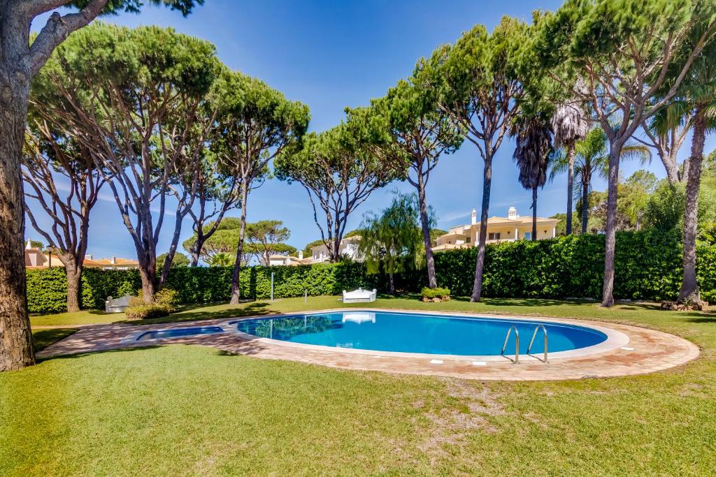 a swimming pool in a yard with trees at Villa Oliveiras de Vilamoura by The Portuguese Butler in Quarteira