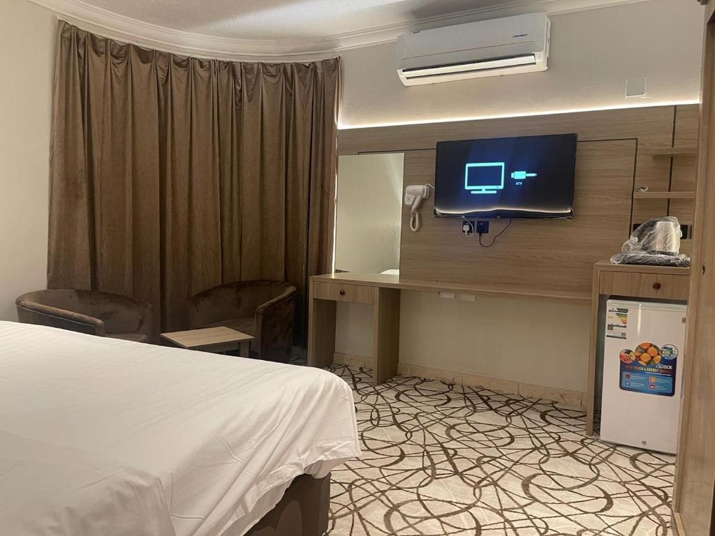 Dvina Hotel في تبوك: غرفة في الفندق بها سرير وتلفزيون على الحائط