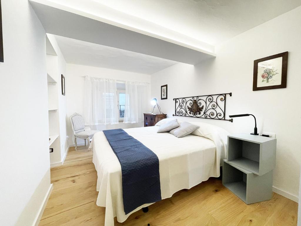 een witte slaapkamer met een groot bed en een stoel bij Il Desiderio zona Piazza del Campo in Siena