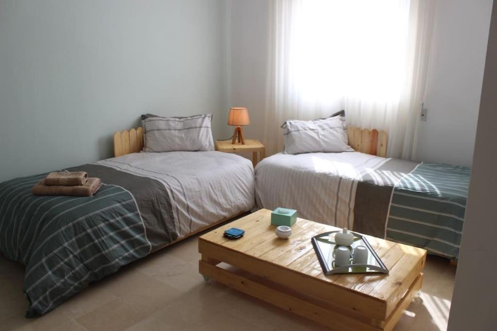 Cette chambre comprend 2 lits et une table basse. dans l'établissement Appartement simple et propre, à Sfax