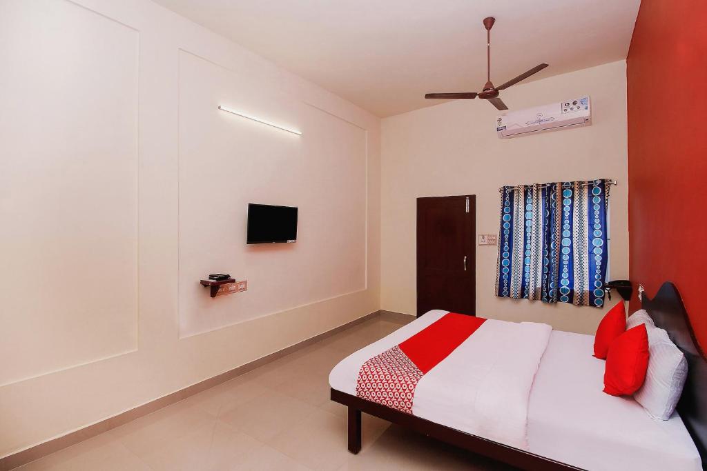 1 dormitorio con 1 cama y TV en la pared en Hotel Aljemin en Kanyakumari
