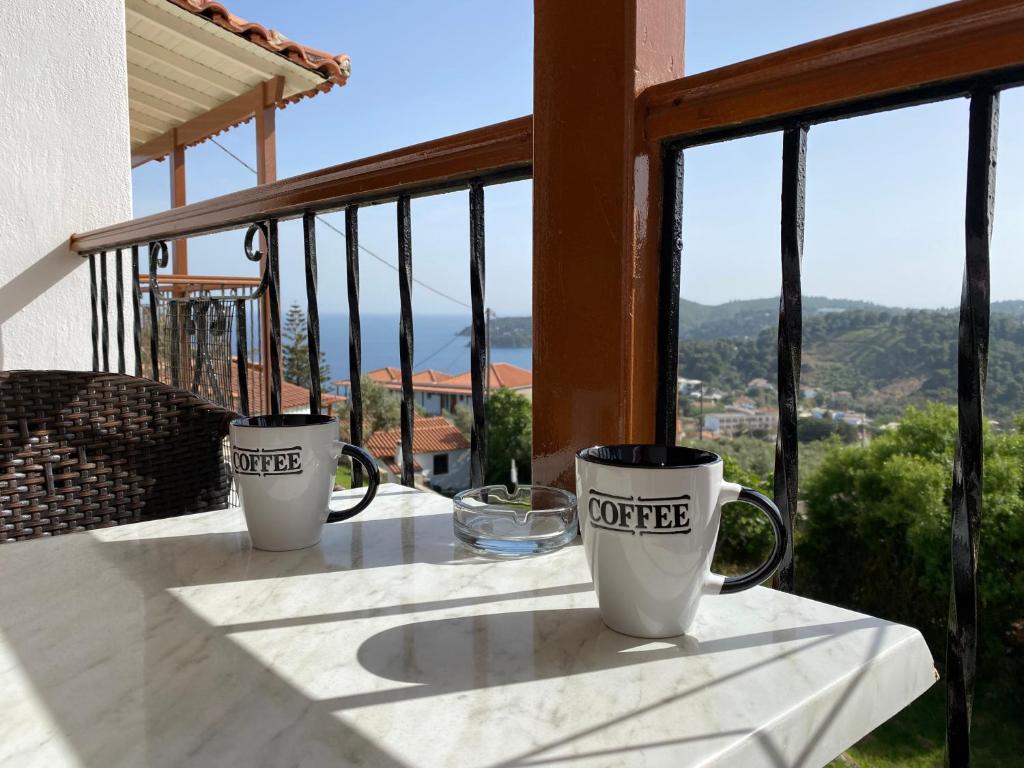 two coffee mugs sitting on a table on a balcony at Valmas village in Skiathos Town