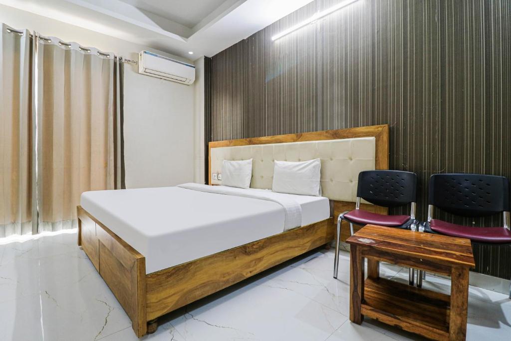 een slaapkamer met een bed en 2 stoelen bij Collection O Hotel Maharaja in Gurgaon