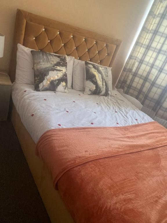 Modern 3 Bed House for 6 guests في Nevendon: سرير عليه بطانية برتقال ومخدات