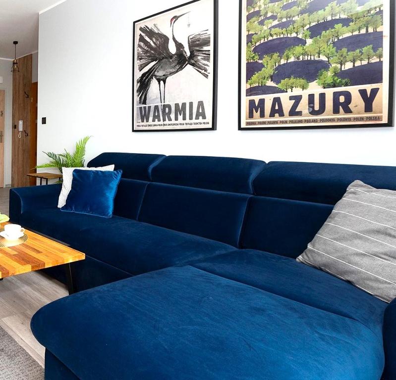 a blue couch in a living room with two posters at City View Apartment in Iława