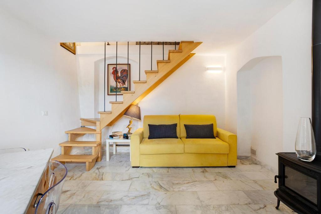 een woonkamer met een gele bank en een trap bij Villino Marco in Luni