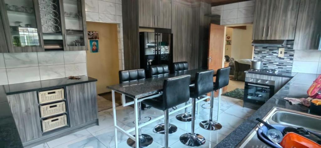 uma cozinha com um bar com cadeiras pretas em Samaz Bliss Gaderns em Delmas