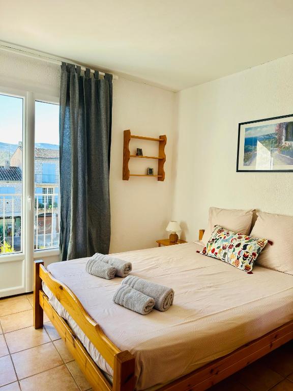 une chambre avec un grand lit et une fenêtre dans l'établissement Les Balcons du Lac T2 Belle vue, aux Salles-sur-Verdon