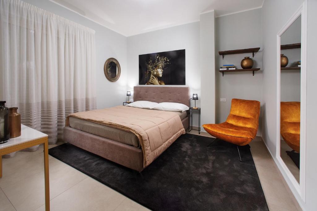 1 dormitorio con 1 cama y 1 silla en Showroom Luxury B&B, en Reggio Calabria