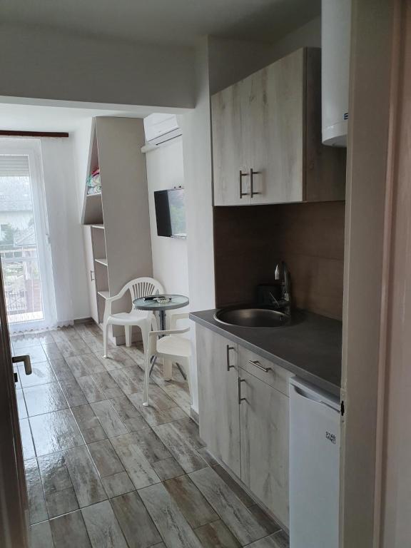 een keuken met een wastafel en een tafel in een kamer bij Farkas Apartmanok in Balatonlelle
