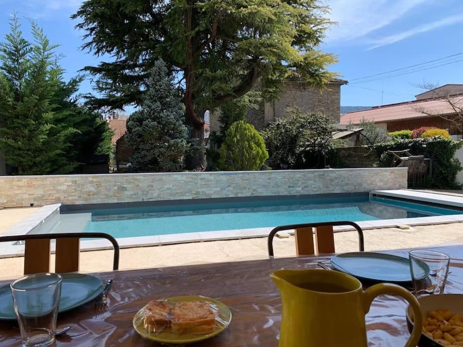 - une table avec une assiette de nourriture à côté de la piscine dans l'établissement Superbe Villa Centre-ville Millau, à Millau