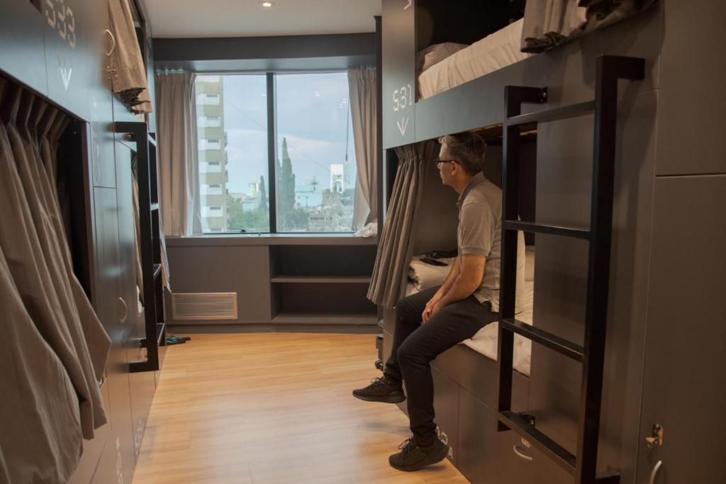 um homem sentado numa prateleira numa sala em MONS hostel em Buenos Aires
