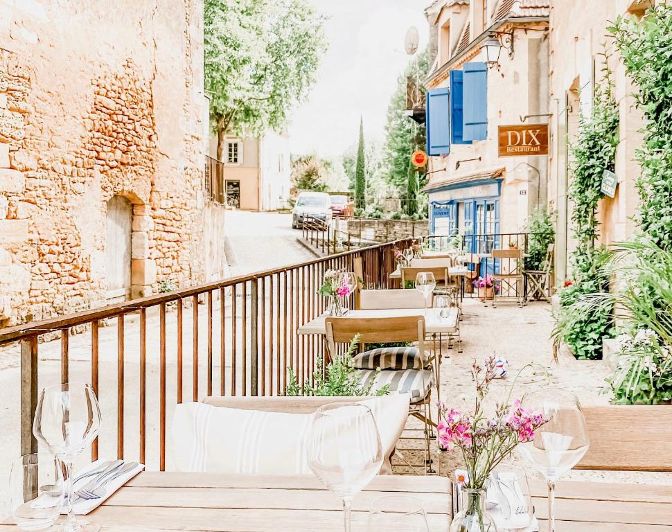 einen Balkon eines Restaurants mit Tischen und Stühlen in der Unterkunft DIX Restaurant & Chambres d'hotes in Saint-Alvère