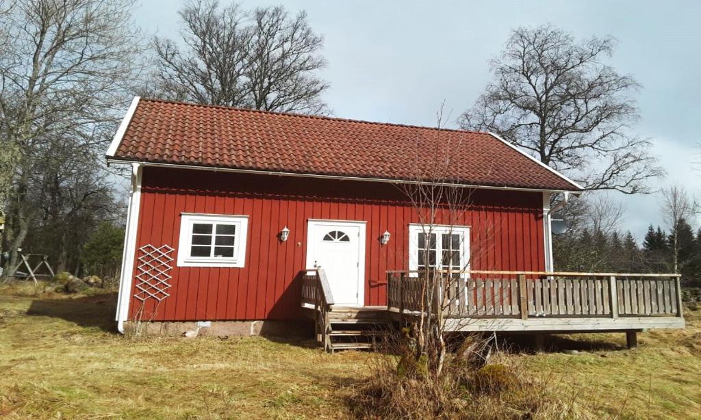 a red house with a deck in a field at Cozy red cottage with white knots outside Lenhovda in Lenhovda