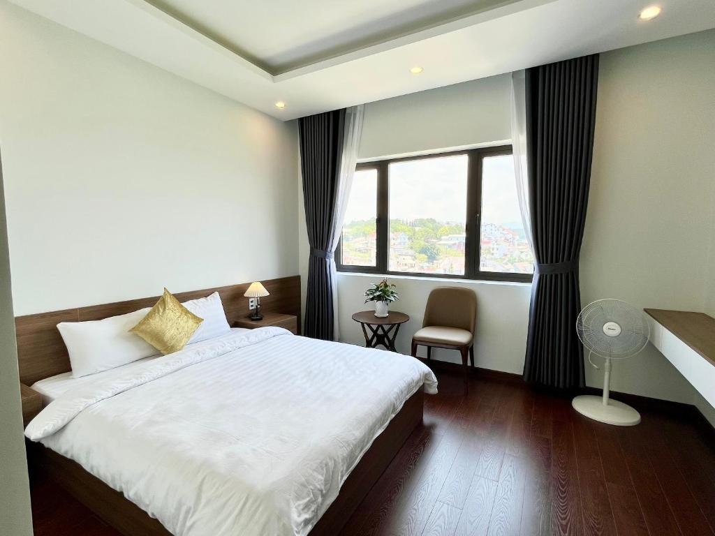 - une chambre avec un grand lit blanc et une fenêtre dans l'établissement SAFFRON Dalat, à Đà Lạt