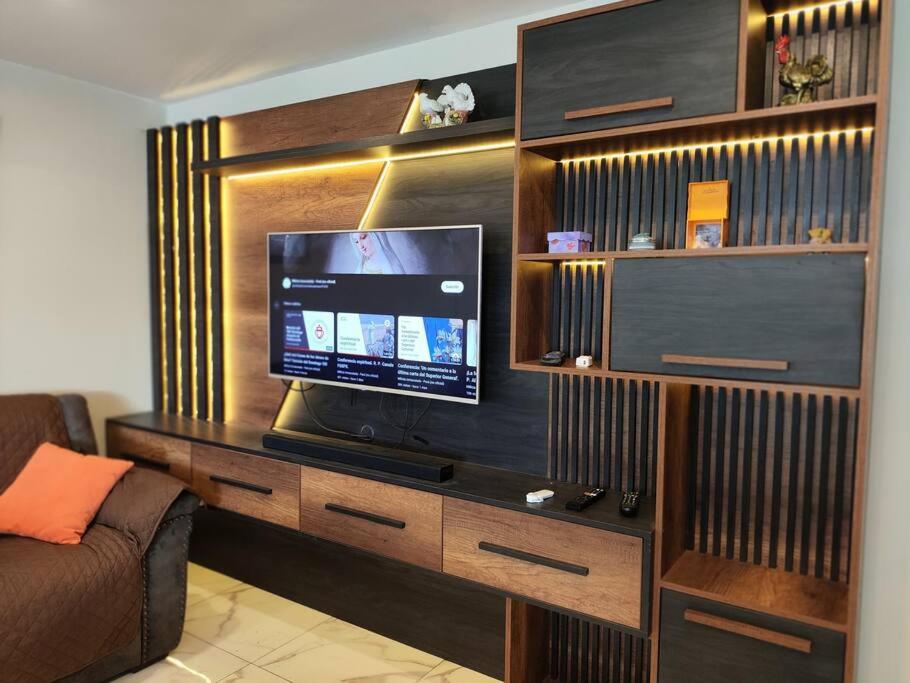 um centro de entretenimento com televisão numa sala de estar em Warm House Near the Airport Callao em Lima
