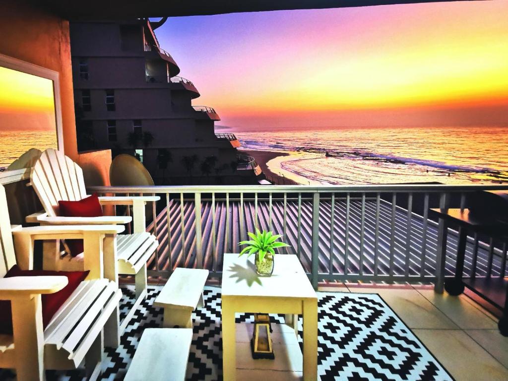 a balcony with a view of the beach at sunset at OCEAN WHISPER II - Power back up, Sea facing, Umdloti in Umdloti