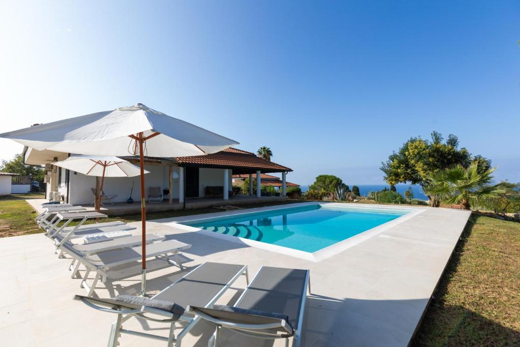 - une piscine avec des chaises longues et un parasol dans l'établissement Villa Serenità - with private pool and ocean view, à Ricadi