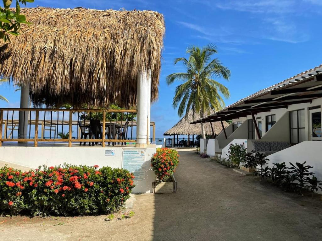 a resort with flowers and a straw roof at Cabañas La Española in Coveñas