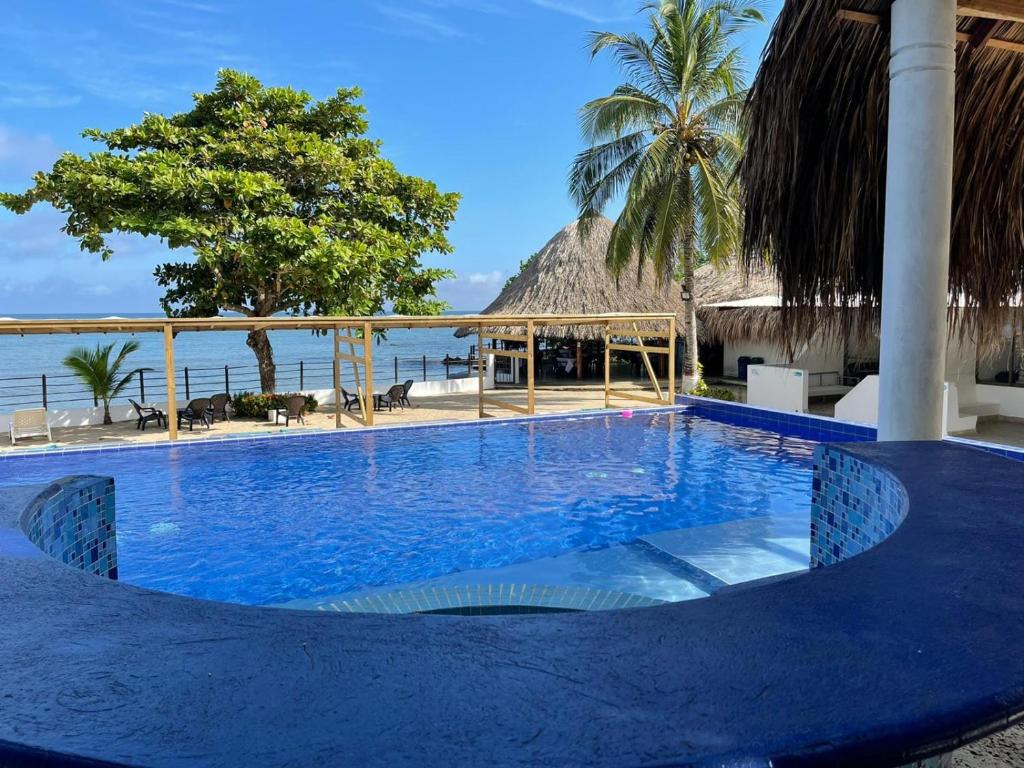 una gran piscina azul junto al océano en Cabañas La Española, en Coveñas
