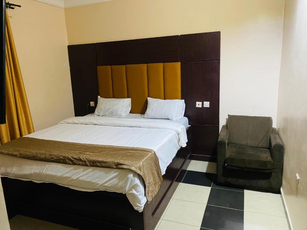 Havilah Suites Ltd, Nnewi في Nnewi: غرفة نوم بسرير كبير وكرسي