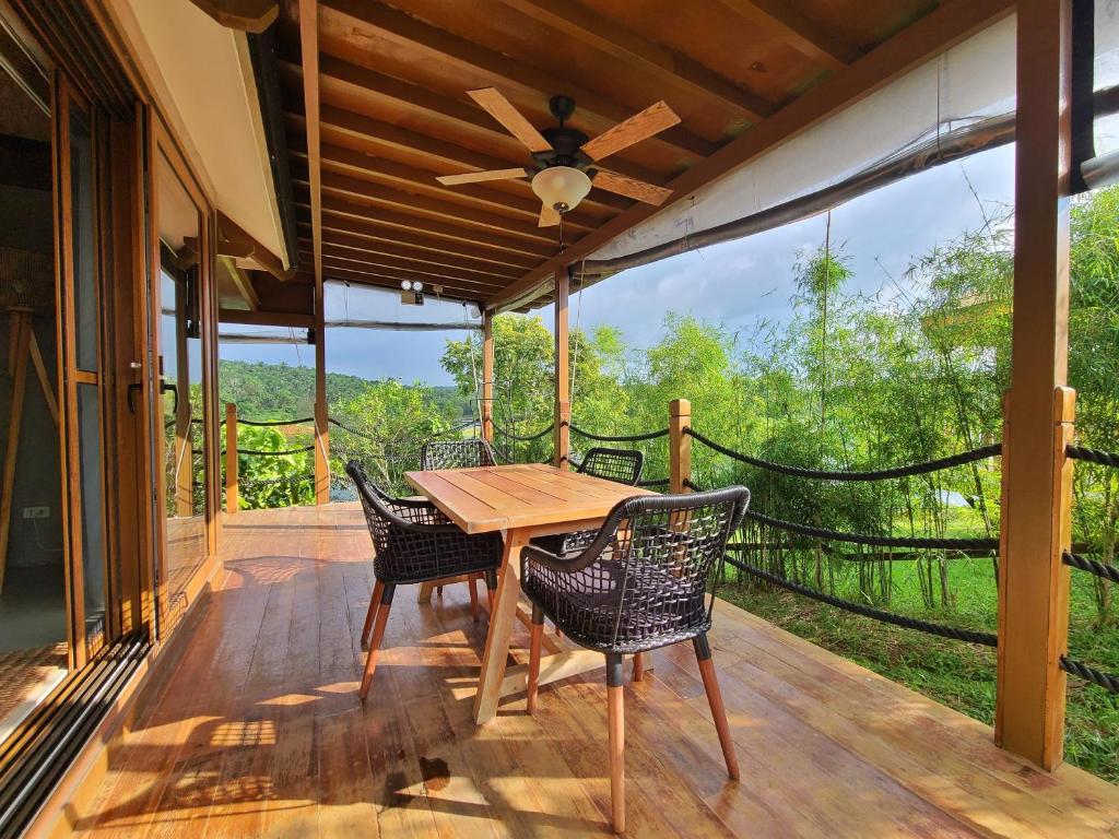 una mesa de madera y sillas en una terraza con ventilador de techo en Sofia's Lake Resort, en Cavinti