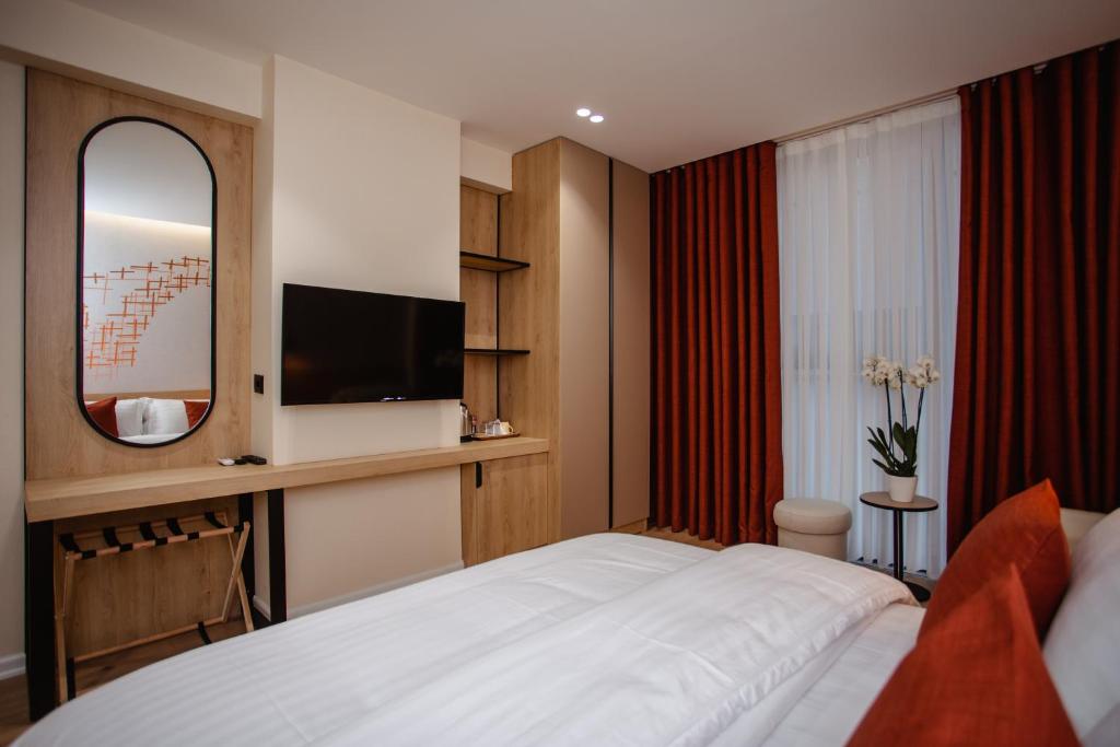 una habitación de hotel con una cama y un espejo en Oro Inn Hotel, en Shkodër