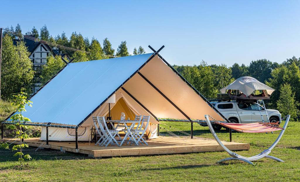 a tent with a table and a truck in a field at Glamping Szelągówka in Sorkwity