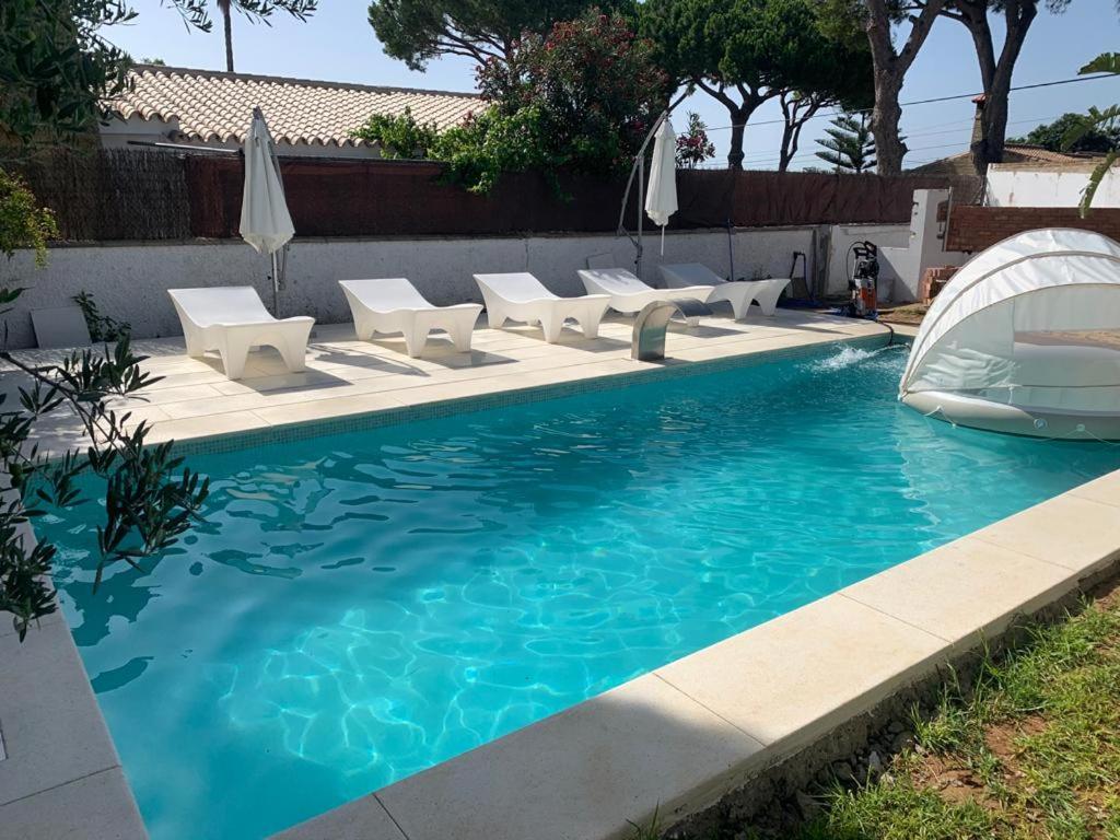 a swimming pool with chairs and umbrellas and a boat at Villa Amaya in El Puerto de Santa María