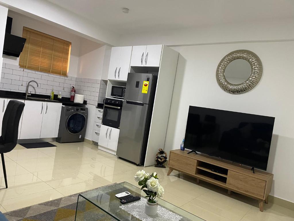 een woonkamer met een flatscreen-tv en een keuken bij Lovely, One bed Flat in Accra. in Accra