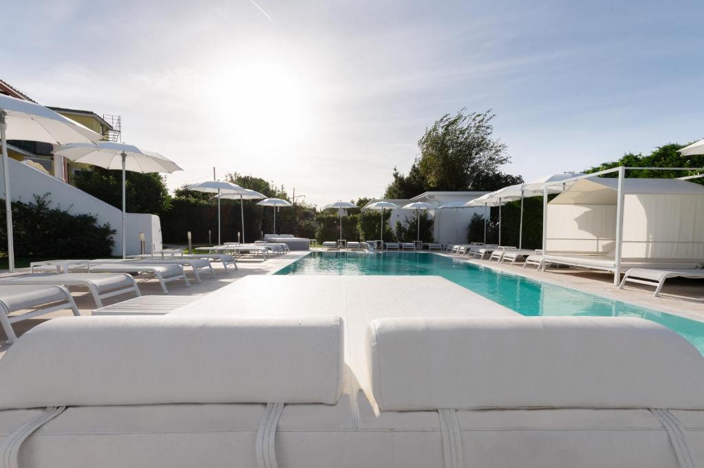 a swimming pool with white lounge chairs and umbrellas at Il Leone Di Mare in Procida