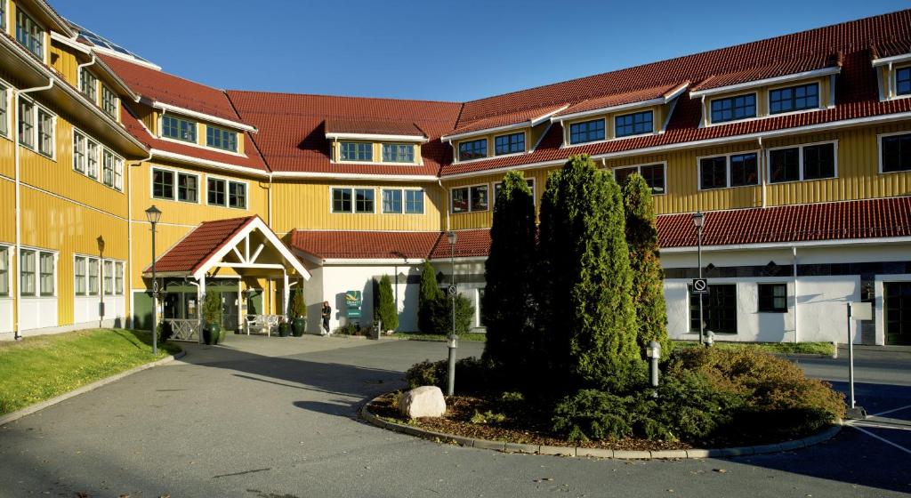 un gran edificio amarillo con un árbol delante de él en Quality Hotel Sarpsborg en Gralum