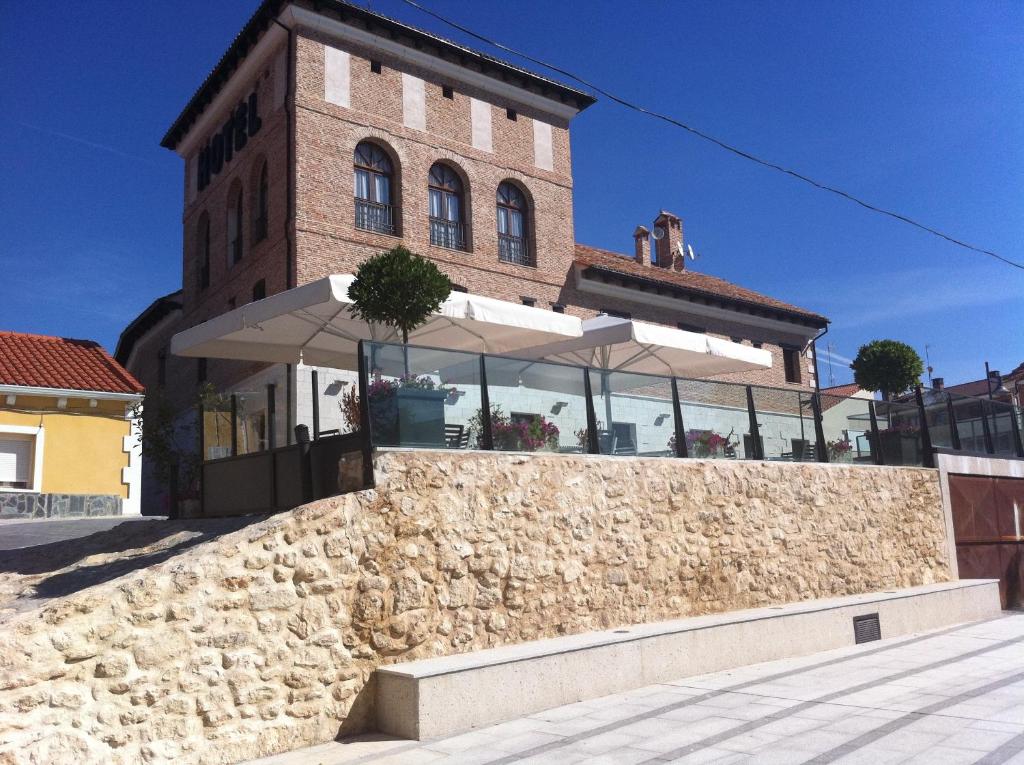 a brick building with an umbrella in front of a wall at Jardin de la Abadia in Valladolid