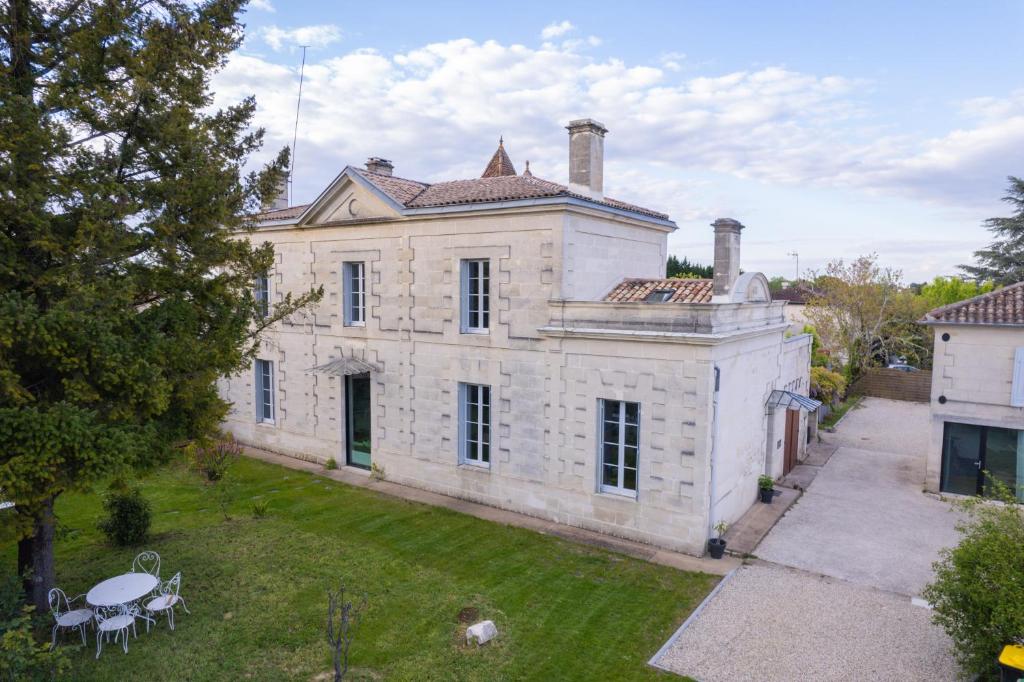 - une vue extérieure sur une grande maison en pierre avec une cour dans l'établissement Le jardin de Gassiot, à Saint-Quentin-de-Baron